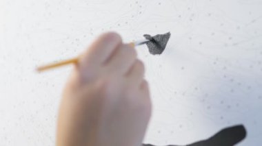 Bir kadın bir resmi numaralarla boyar. Kız çizim için bir fırça tutuyor ve siyah akrilik boyalarla bir resim çiziyor. Yüksek kalite 4k görüntü