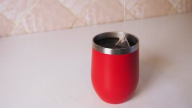Bir kadının eli, çay poşetini kırmızı kupaya indirir. Kız mutfakta çay hazırlıyor. Yüksek kalite 4k görüntü