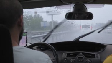 Beyaz sakallı bir adam yağmur yağdığında otoyol boyunca araba sürer. Bir adam şehir yolunda bir araba deresine biniyor. Yüksek kalite 4k görüntü