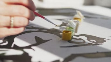 Bir kadın bir resmi numaralarla boyar. Kız çizim için bir fırça tutuyor ve siyah akrilik boyalarla bir resim çiziyor. Yüksek kalite 4k görüntü