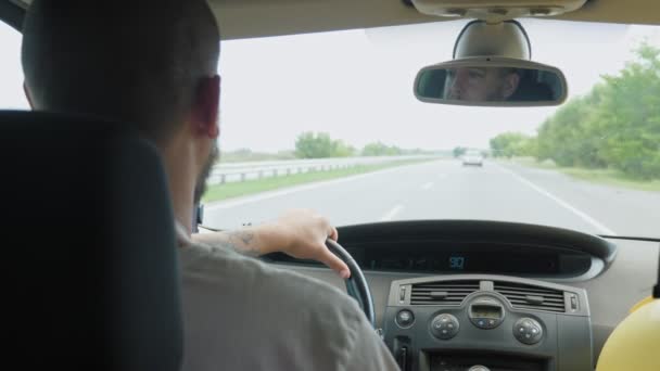 短髪の髭の男が街の外の高速道路に沿って車を運転している 髭を生やした男が休暇で家族を連れて行っている 高品質4K映像 — ストック動画