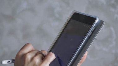 Kız tablete bir stil çiziyor. Kadınların elleri tabletle yakın plan çekimde. Kız mavi arka planda yıldızlar çiziyor. Yüksek kalite 4k görüntü