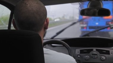 Beyaz sakallı bir adam yağmur yağdığında otoyol boyunca araba sürer. Bir adam şehir yolunda bir araba deresine biniyor. Yüksek kalite 4k görüntü