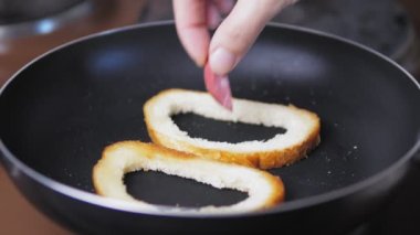 Sosisli tostlar tavada kızartılır. Çiğ yumurta bir dilim ekmeğin üzerinde kırılır. Ev yapımı kahvaltı fikri. Yumurtalı tostu yakından çek. Yüksek kalite 4k görüntü