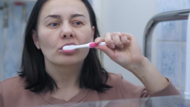 Tmavovlasá Běloška Čistí Zuby Když Stojí Před Zrcadlem Koupelně Ranní — Stock video