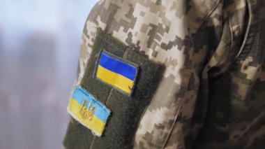 Üzerinde sarı ve mavi bir sembol olan askeri üniformalı bir adamın omuzları. Ukrayna ordusunun askeri, Ukrayna 'nın savunucusu. Yüksek kalite 4k görüntü