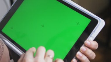 Elinde yeşil ekranı olan bir tablet tutan beyaz bir kız. Ekranda kroma anahtarı olan bir aletle kadın ellerine yakın çekim. Yüksek kalite 4k görüntü