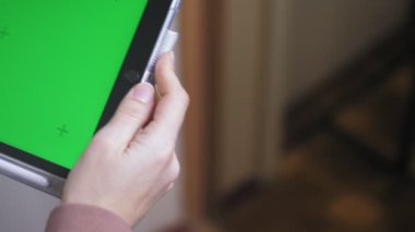 Elinde yeşil ekranı olan bir tablet tutan beyaz bir kız. Ekranda kroma anahtarı olan bir aletle kadın ellerine yakın çekim. Yüksek kalite 4k görüntü