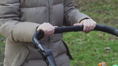 Bir kadının elleri yürüyüş sırasında bebek arabasını ittirirken. Anne ve küçük kızı parkta, bebek arabasında uyuyan bebek. Yüksek kalite 4k görüntü