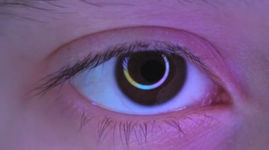 Close-up of teenagers eye, a reflection of circular RGB lamp in the eye. High quality 4k footage