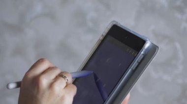 Kız tablete bir stil çiziyor. Kadınların elleri tabletle yakın plan çekimde. Kız çizim için gerekli rengi seçer. Yüksek kalite 4k görüntü