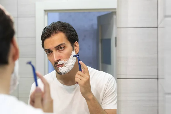 英俊的男人看着镜子 在浴室里刮胡子 — 图库照片