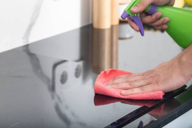 Erkek ellerinin şişe spreyi tutarken ve sobayı temizlerken yakın çekim.