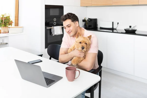 Boldog Jóképű Férfi Átöleli Kutyáját Norwich Terrier Dolgozik Laptop Otthon — Stock Fotó