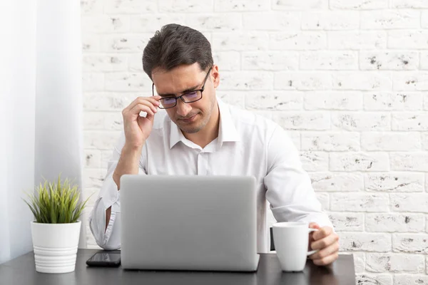 stock image Young handsome businessman working on laptop at home. Distant work concept