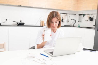 Masada oturan, faturalar ve faturalardan kaynaklanan masraflar yüzünden kafası karışık ve şaşkın kadının ev kredisi veya kredi ödeyecek parası yok. Yüksek fiyatlar ve harcama parası kavramı