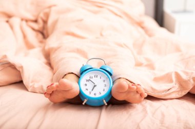 Çalar saatin ve uyanmaya çalışan kadının yakın fotoğrafını çek.