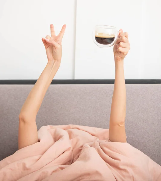 女性手捧着一杯热咖啡躺在床上 喝咖啡和醒悟的概念 — 图库照片