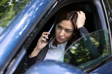 Takım elbiseli genç ve çekici bir iş kadını trafikte dikiliyor ve cep telefonuyla konuşuyor. Uzun süren trafik ışığı yüzünden yorgun iş kadını arabada oturuyor ve kendini kötü hissediyor.