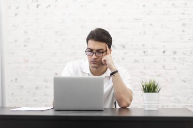 Genç yakışıklı iş adamı evde dizüstü bilgisayarla çalışıyor. Uzak çalışma konsepti