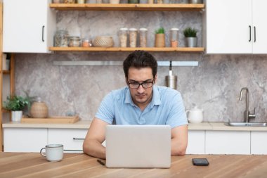 Evde dizüstü bilgisayarla çalışan genç bir iş adamı. Uzak çalışma konsepti