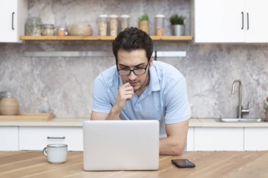Gülümseyen iş adamı evde masada oturuyor ve çalışıyor. Uzak çalışma konsepti