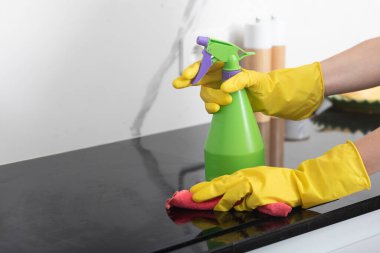 Kadın eli, elinde şişe spreyi ve fırını temizlemek için bez parçasıyla yakın çekim.