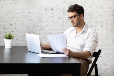 Ciddi bir iş adamı evdeki masada oturuyor ve çalışıyor. Uzak çalışma konsepti