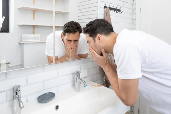 stock image Handsome man washing his face in the bathroom. Morning routine and hygiene concept