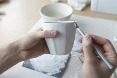 Kil kupa ile çalışan ve seramik ürün yapan ellerin yakın plan görüntüsü. Profesyonel Seramik Sanatçısı el yapımı ürünler yapıyor. Küçük işletme ve hobi konsepti