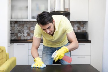 Evi temizledikten sonra mutfakta yorgun ve sıkılmış bir adam masasını temizliyor. Yorgun ev konsepti