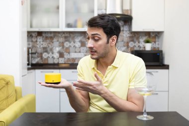 Adam akıllı hoparlör ile iletişim kuruyor müzik sütunu ses asistanı ve akıllı telefonu ile