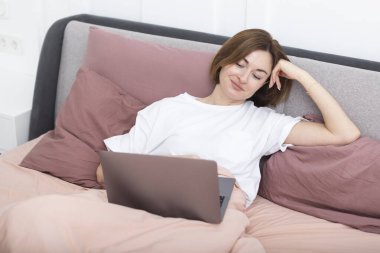 Şaşırmış kız yatak odasında bilgisayarına bakıyor.