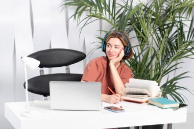 Kulaklıklı genç ve çekici bir kadın evde internetten öğreniyor. Uzaklık eğitimi kavramı