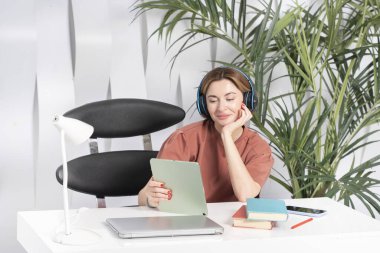 Kulaklıklı genç ve çekici bir kadın evde internetten öğreniyor. Uzaklık eğitimi kavramı