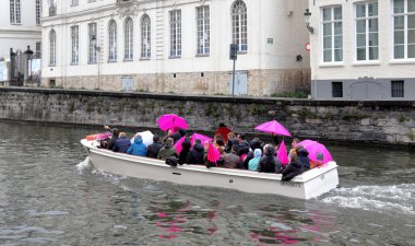 Bruges, Belgium - November 4, 2022: Sightseeing boat trip in canal of Bruges on a rainy day.