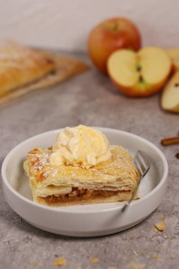 Elmalı turtanın bir parçasını tarçınlı ve dondurmalı gri mermer masanın üstünde, arka planda elmalar. Şükran Günü çöl yemeği. Yüksek kalite fotoğraf