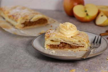 Elmalı turtanın bir parçasını tarçınlı ve dondurmalı gri mermer masanın üstünde, arka planda elmalar. Şükran Günü çöl yemeği. Yüksek kalite fotoğraf