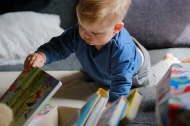 Küçük çocuk kanepede kitaplar ve doldurulmuş hayvanlarla oynuyor. Yüksek kalite fotoğraf