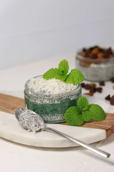 delicious vegan coconut chia pudding with spirulina and mint, on white table. High quality photo