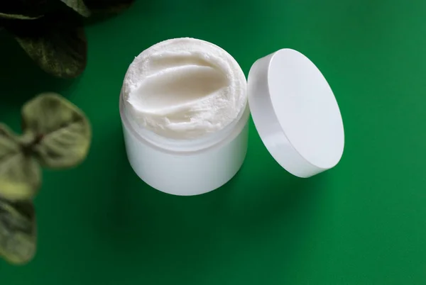mock up of white jar of cream on a green background, with copy space . High quality photo
