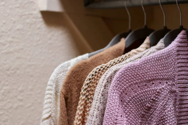 stock image close up of pastel warm knitted cardigan sweater hanging in the closet. Cozy fall and winter wardrobe. High quality photo