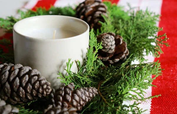 christmas composition with a candle, pine cones and green needles with red table runner . High quality photo