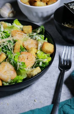 Gri mermer masada ızgara karides, kızarmış ekmek ve parmesan peynirli Cesar salatası yakın. Yüksek kalite fotoğraf