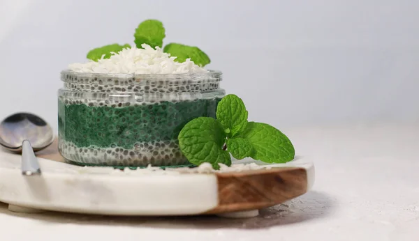 delicious vegan coconut chia pudding with spirulina and mint, on white table. High quality photo