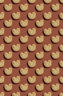 Kahverengi arka planda kalp şeklindeki kurabiyelerin kusursuz deseni. Yüksek kalite fotoğraf