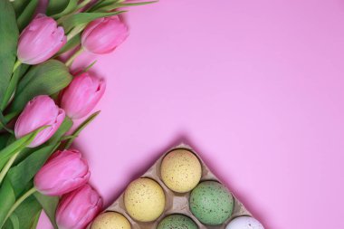 pink Easter background with tulips and colourful eggs . Copy Space with top view