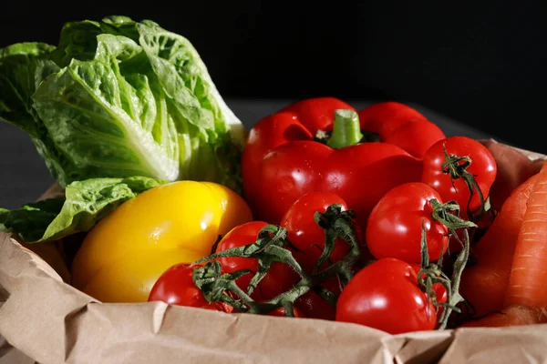 stock image close up of fresh vegetables in eco paper bag, dark background . Clean vegan eating concept. 