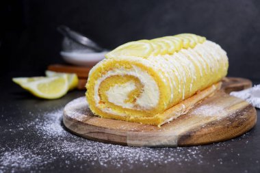 close up of delicious vanilla cake roll with lemon butter cream inside, grey marble table