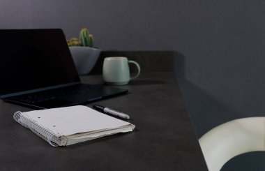 Boş dizüstü bilgisayarı ve gri mermer masada yeşil kahve fincanı olan boş defteri kapat.